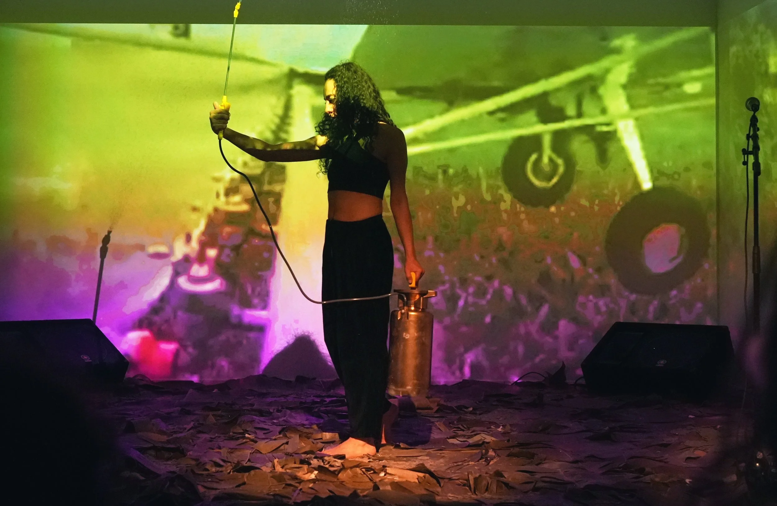 Person with a hand-held sprayer standing on a mat made of banana leaves—performance coca para comer