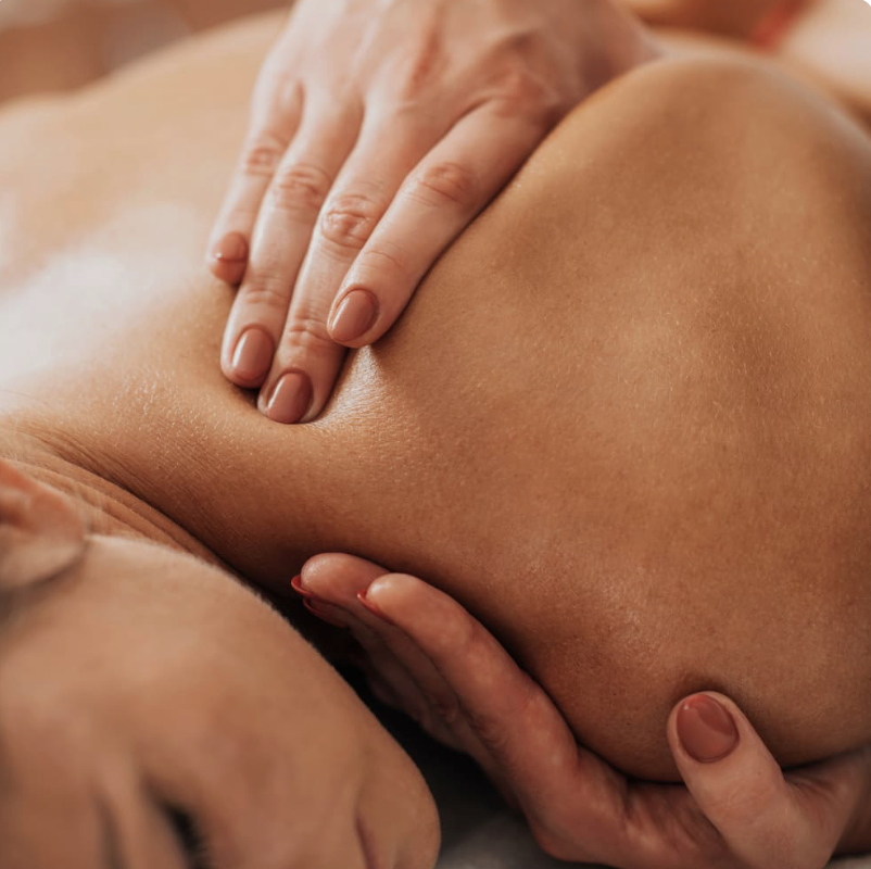 Close-up of a person receiving a massage on their back and shoulder area, with hands applying pressure.