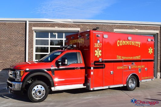 Red fire rescue vehicle with community and fire prevention markings parked outside a building.