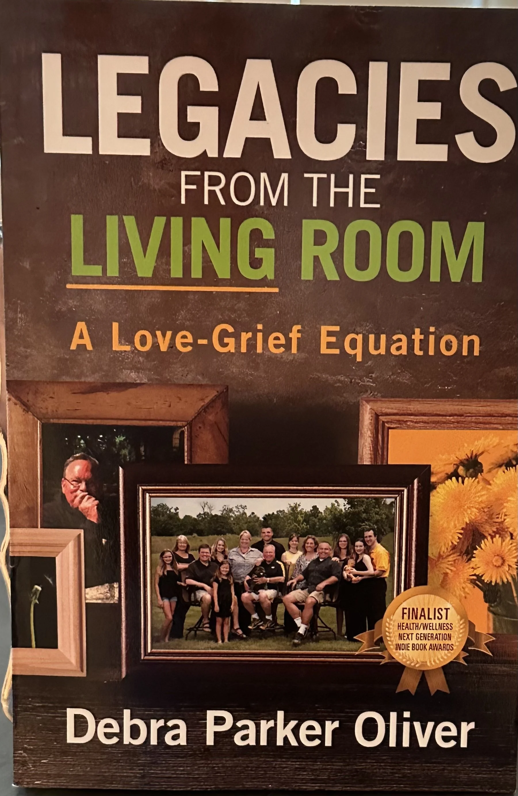 A poster featuring a large photograph of a group of people outdoors, framed with other photos and decorative elements. The poster promotes a person named Deborah Parker Oliver, highlighting her achievements as a finalist in health/wellness and next generation indie book awards.