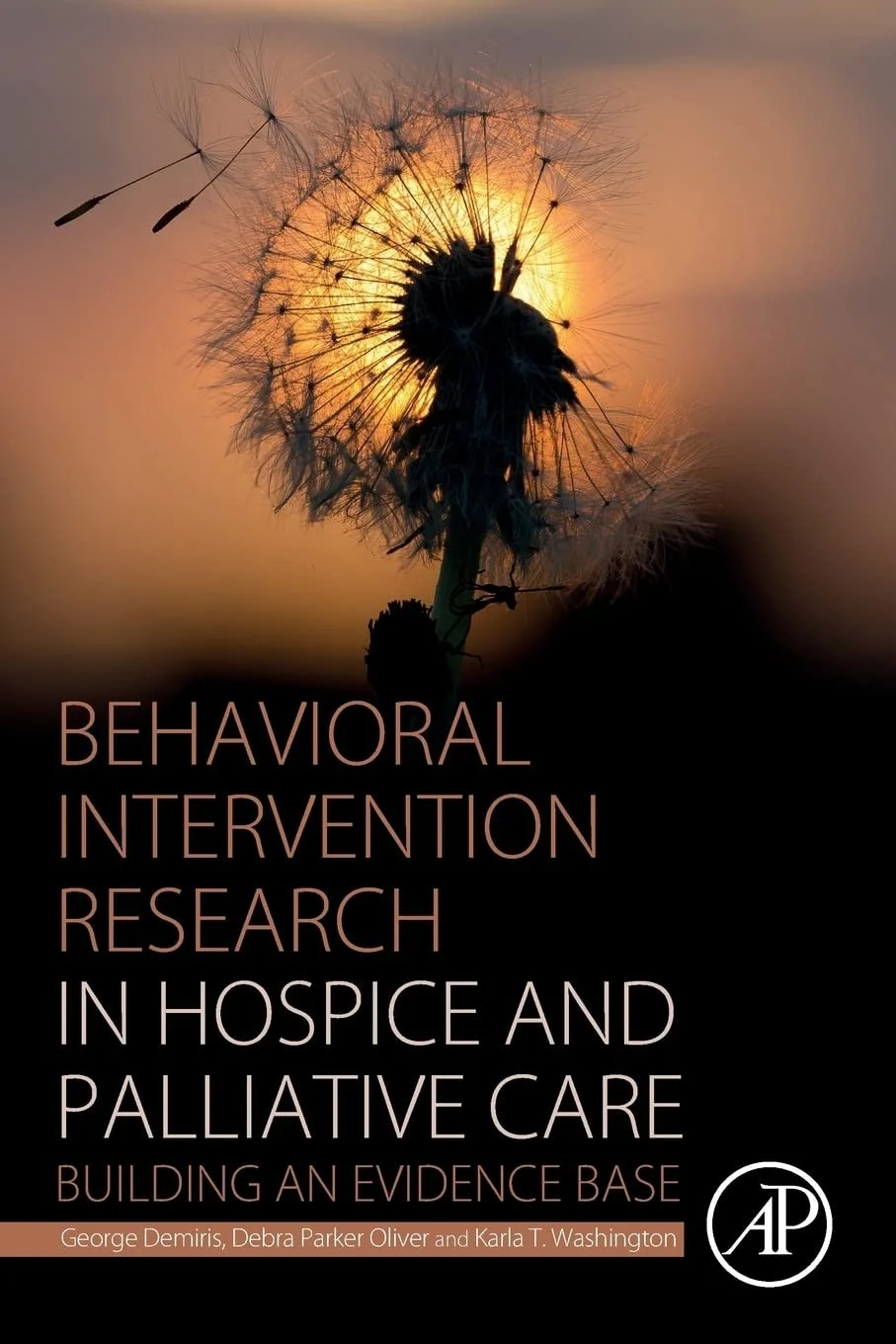 Book cover showing a dandelion silhouette against a sunset sky, with the title "Behavioral Intervention Research in Hospice and Palliative Care: Building an Evidence Base" and authors George Demiris, Debra Parker Oliver, and Karla T. Washington.