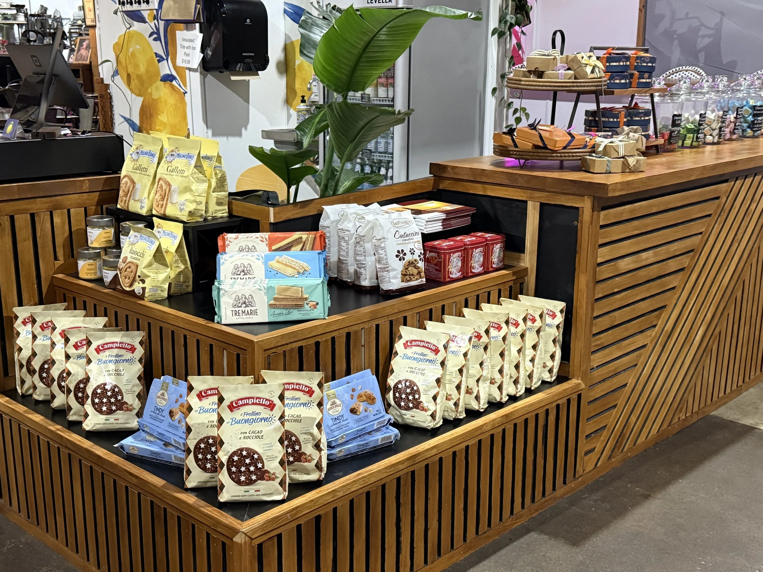 Display of various packaged baked goods, including cookies and biscuits, arranged on wooden shelves inside a store.