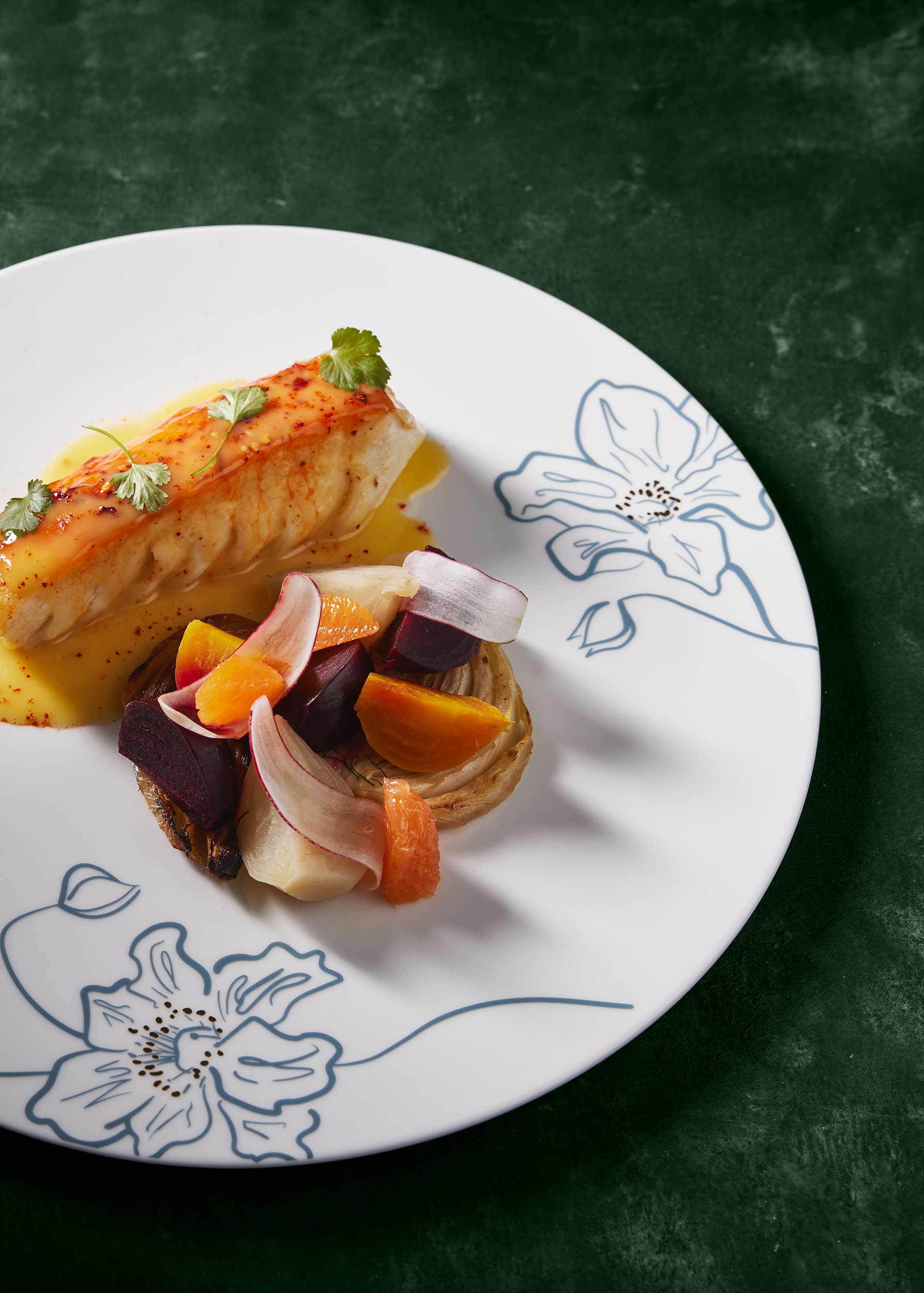 Halibut garnished with microgreens and served with a side of roasted vegetables.