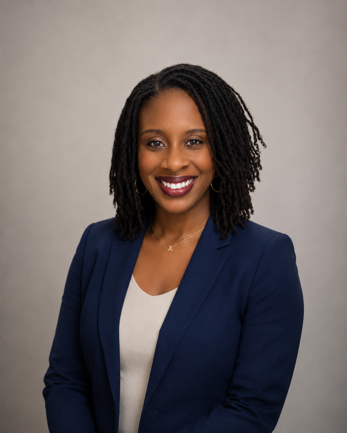 Professional woman with shoulder-length textured hair, wearing a navy blazer and a white top, smiling against a neutral background.