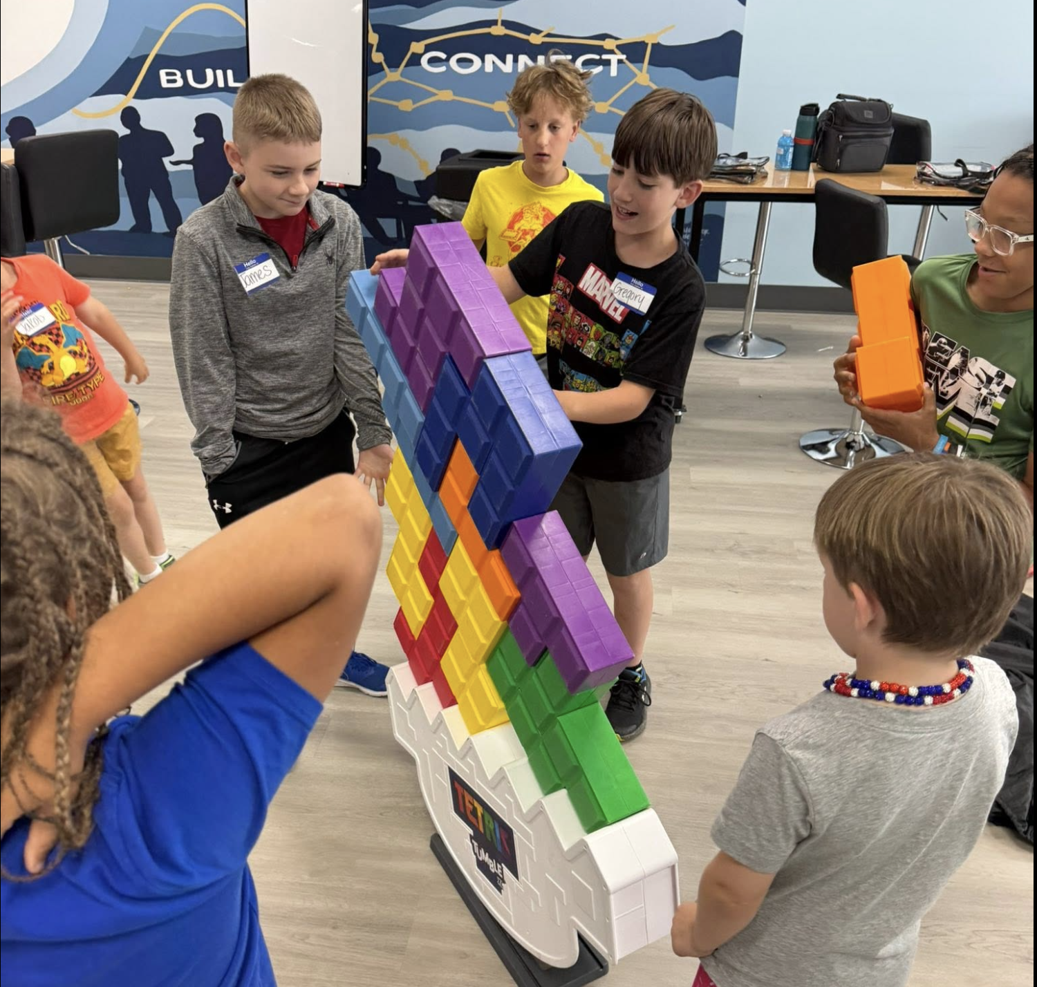 Children building a colorful Tetris tower with large plastic pieces during an educational activity.