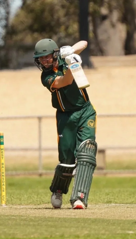 Cricket player in green uniform batting on the field