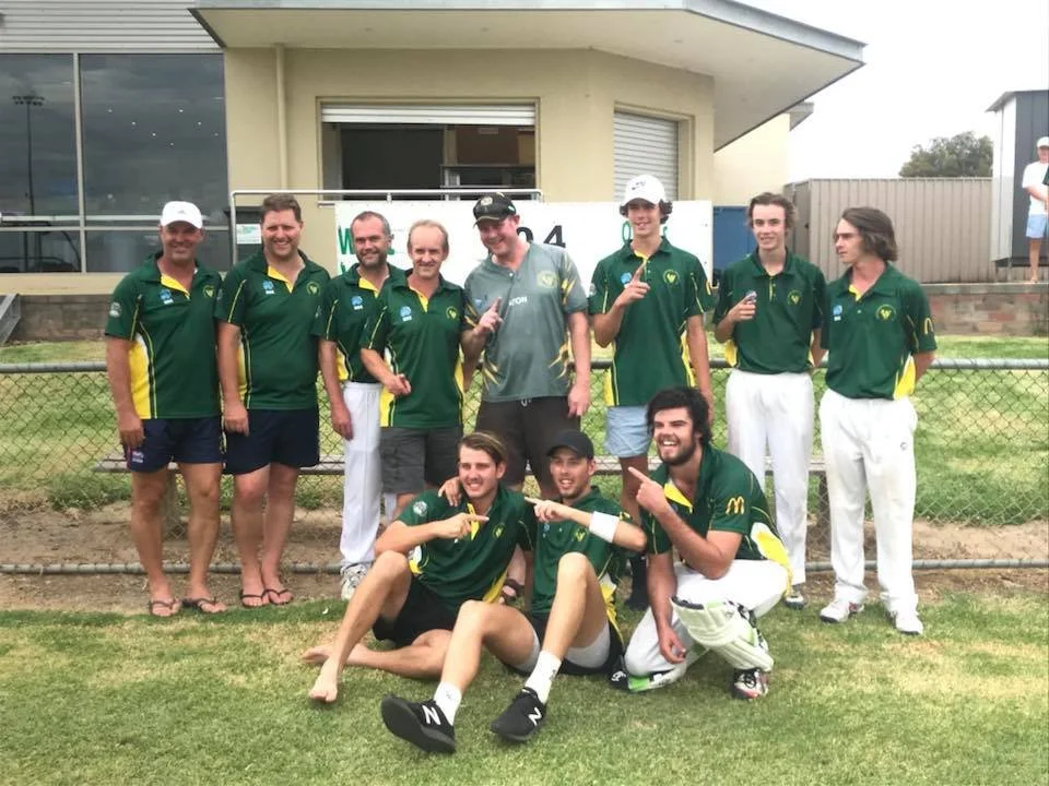 A group of cricket players in green and yellow uniforms celebrating on a cricket field.
