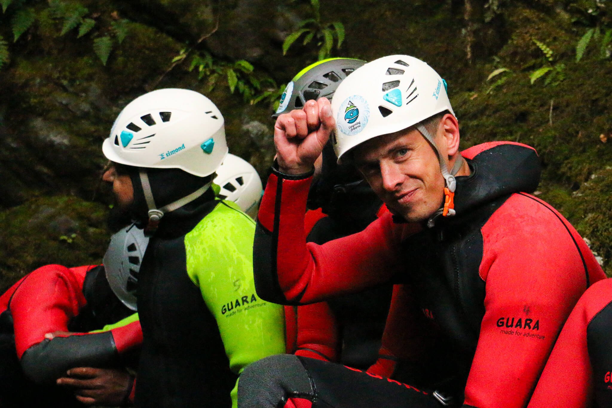 Group of canyoners wearing helmets and red jackets, possibly in a forested area during training or emergency operation.