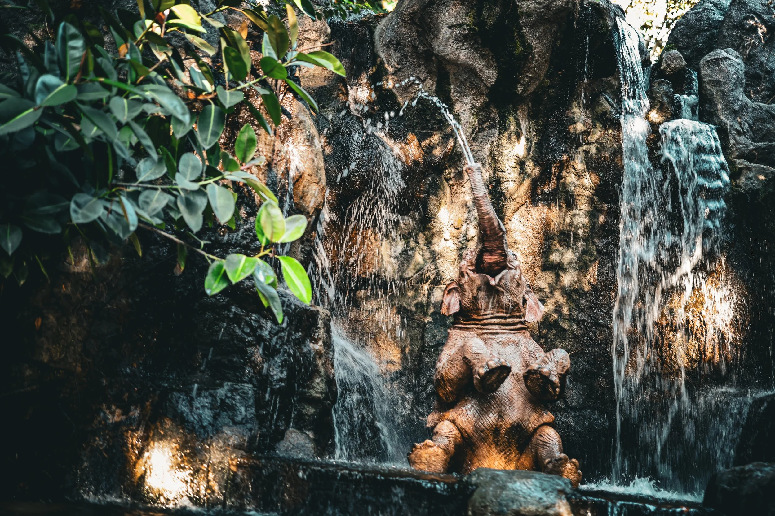 Close-up of a small waterfall over rocks with greenery on the left side.
