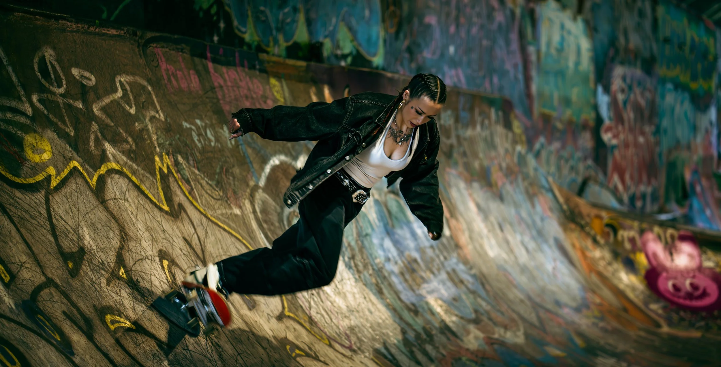 A person skateboarding in a graffiti-covered skatepark with colorful street art on the walls.