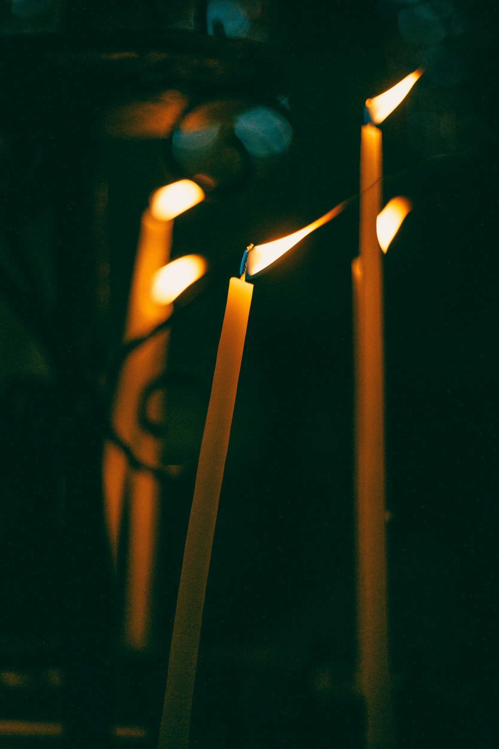 Close-up of burning candles with blurred background, warm glow, dark ambient lighting