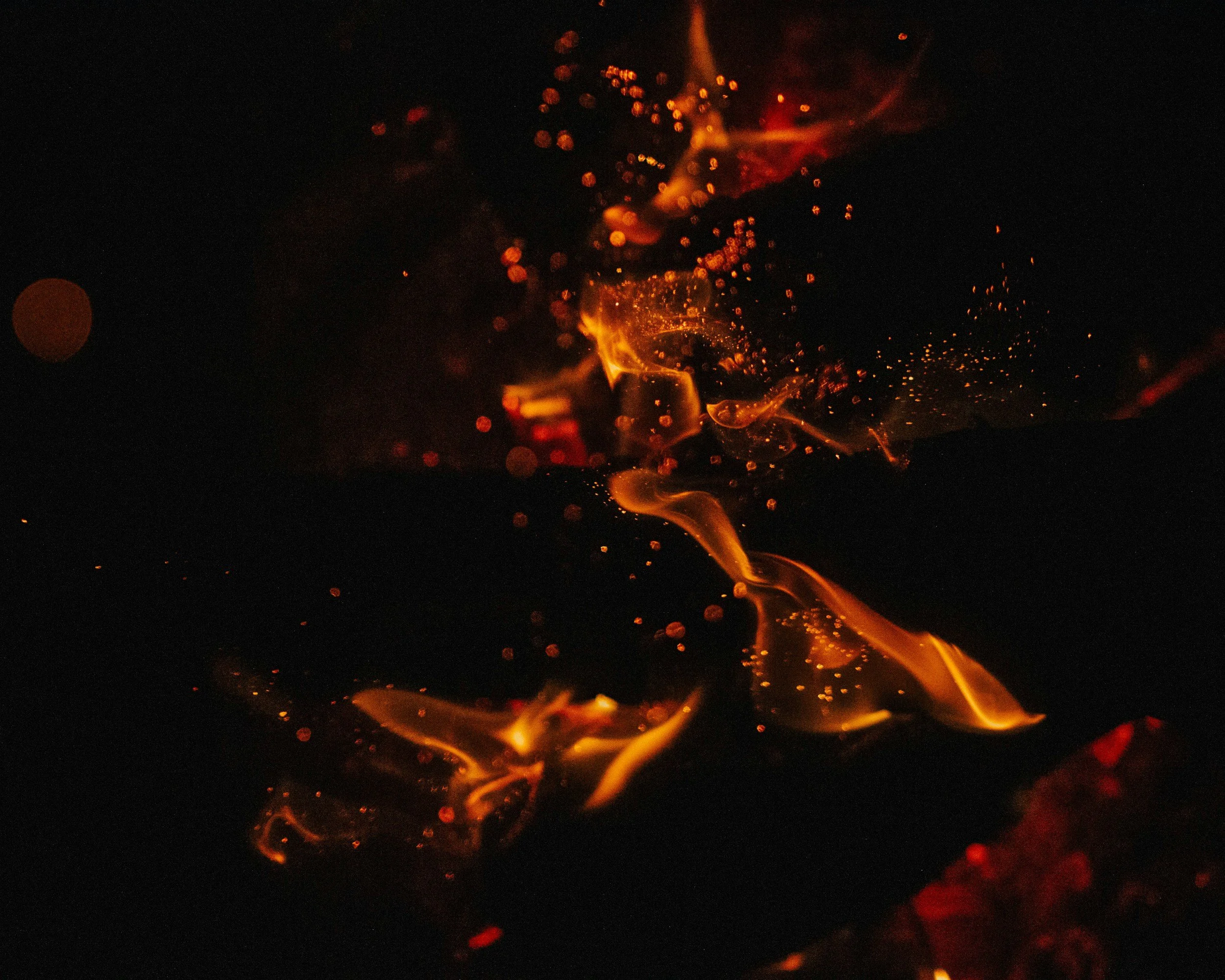 Burning embers and sparks in a dark environment with orange and red flames.