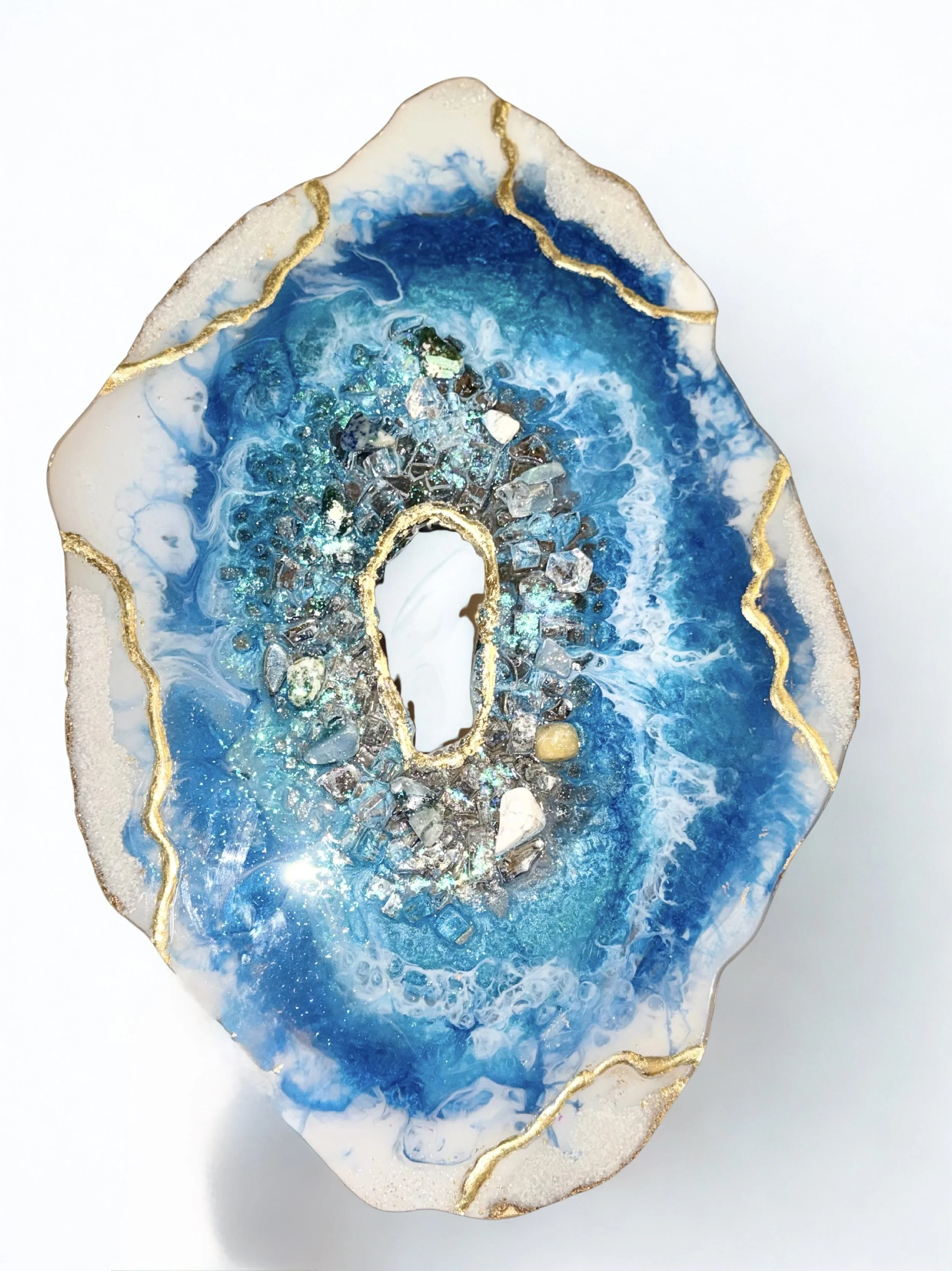 A decorative geode with blue, white, and gold accents, featuring crystals and swirling patterns.