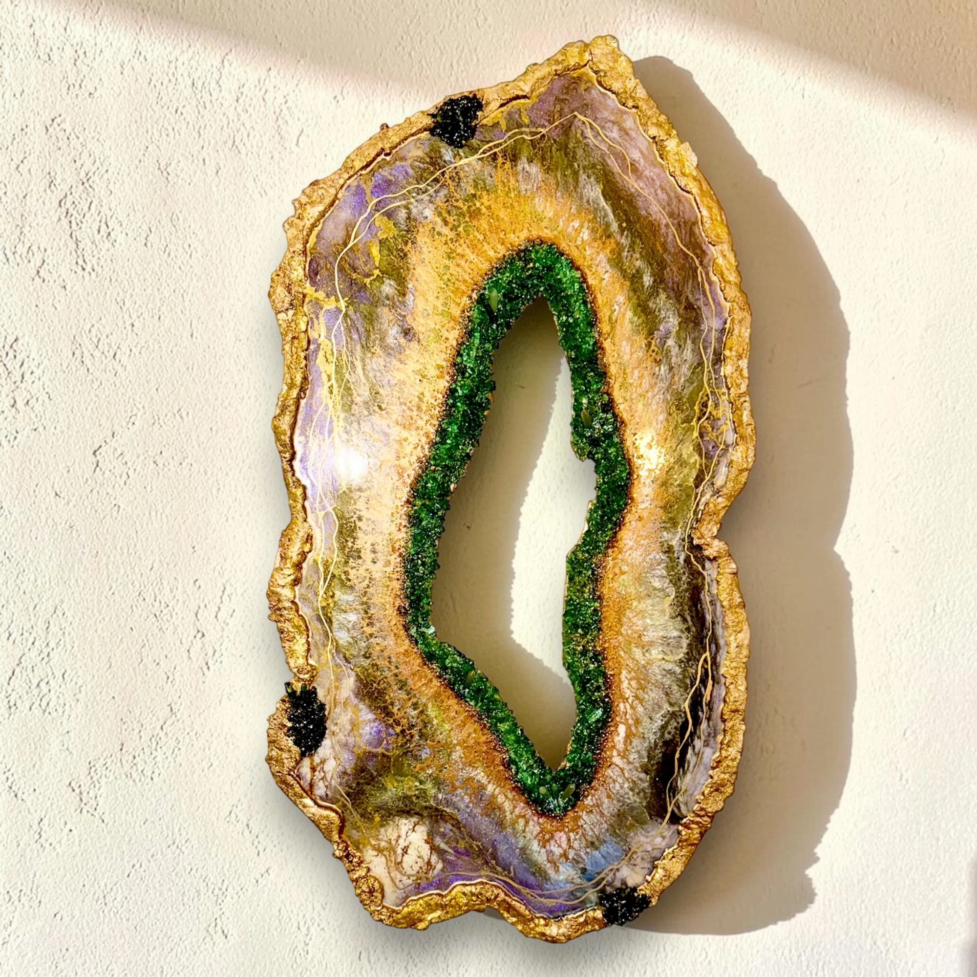 Decorative stone resembling a rainbow with purple, yellow, green, and black accents, mounted on a white textured wall.