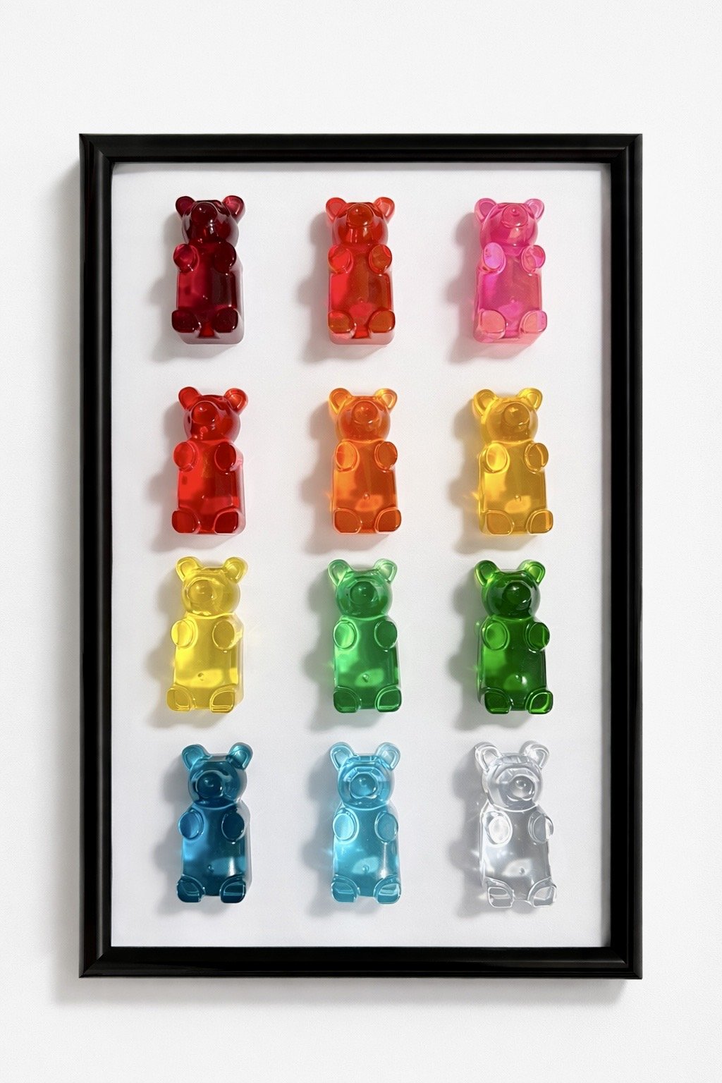 Colorful gummy bear-shaped objects arranged in a framed display, in three rows with three in the first row, three in the second, and three in the third, on a white background.