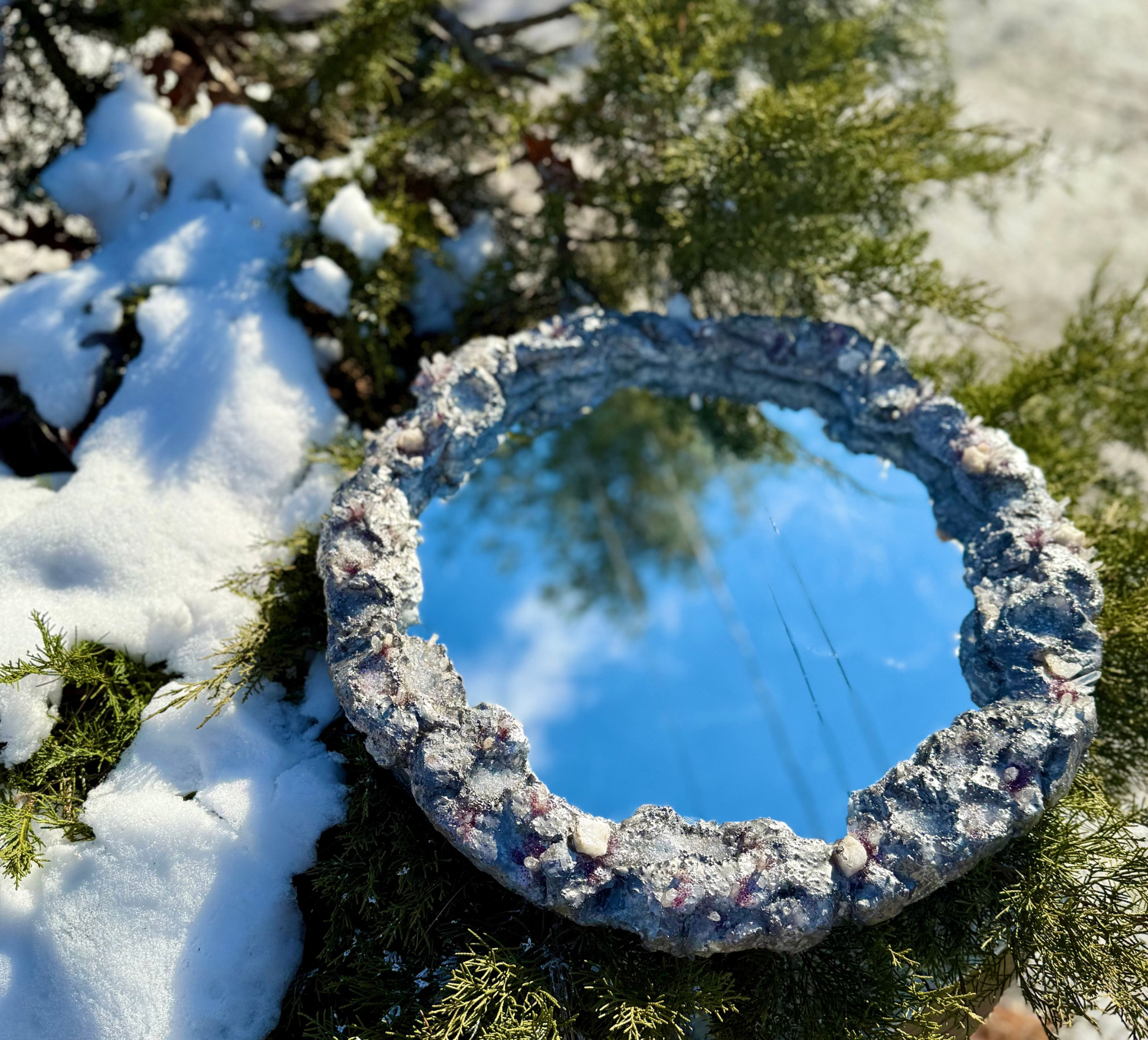 Close-up of snow-covered tree branches and green pine needles with a clear blue sky in the background.