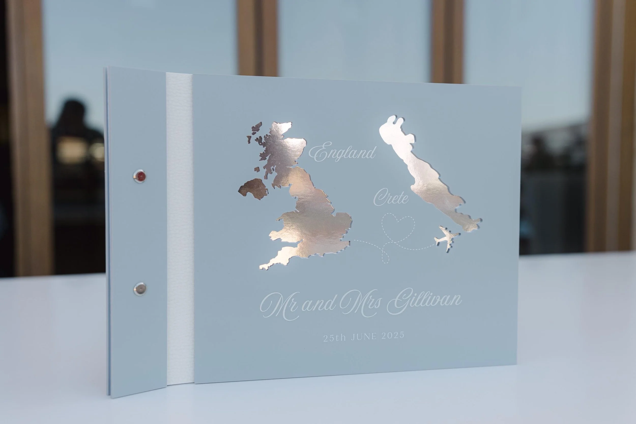 Blue acrylic destination wedding guestbook with reflective map silhouettes and white lettering