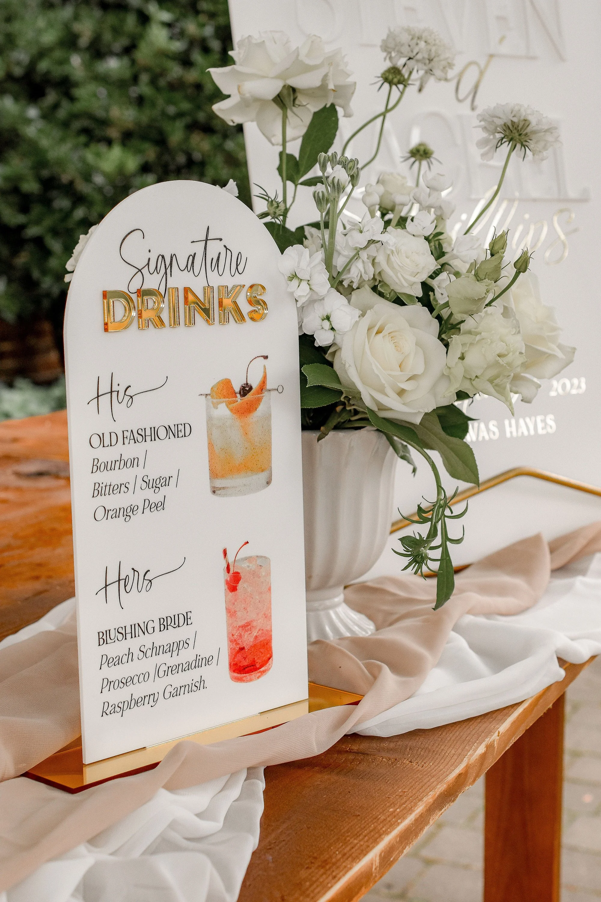 Colourful acrylic wedding bar sign displayed with flowers and signature cocktails