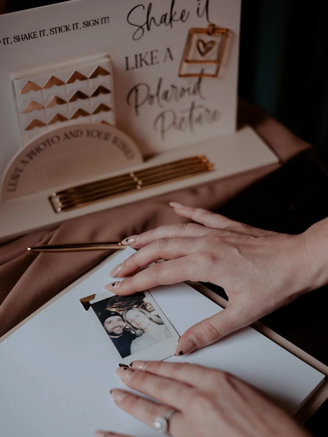 Photo corners being used to attach an instant photograph to a wedding guestbook page.