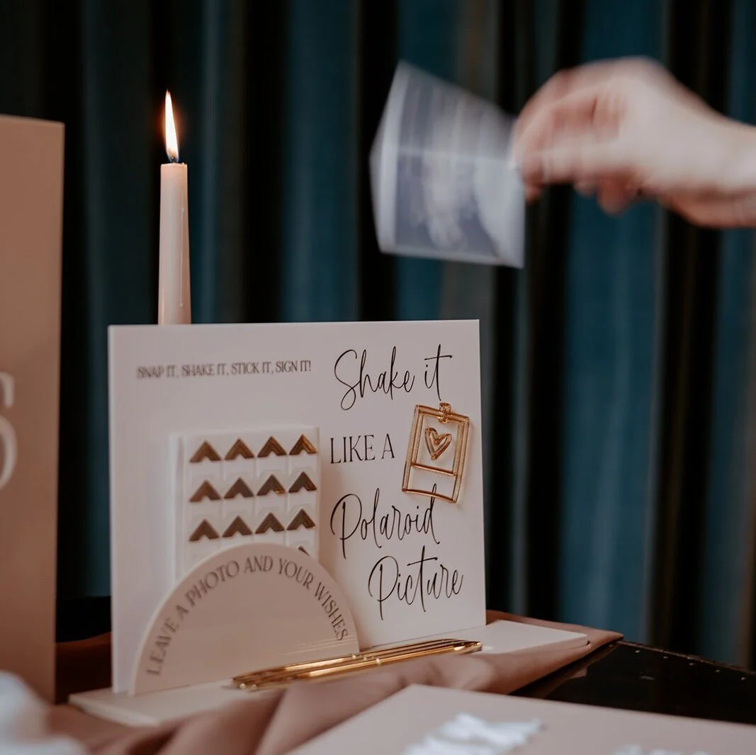 Polaroid wedding guestbook station with instruction sign, camera and instant photographs.