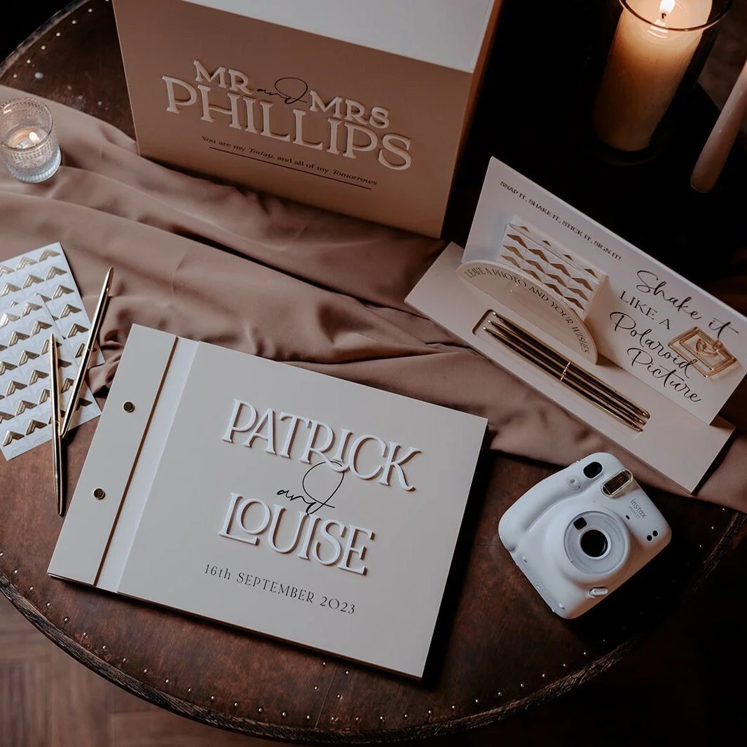 Personalised wedding photo guestbook setup with an acrylic Polaroid sign and accessories.