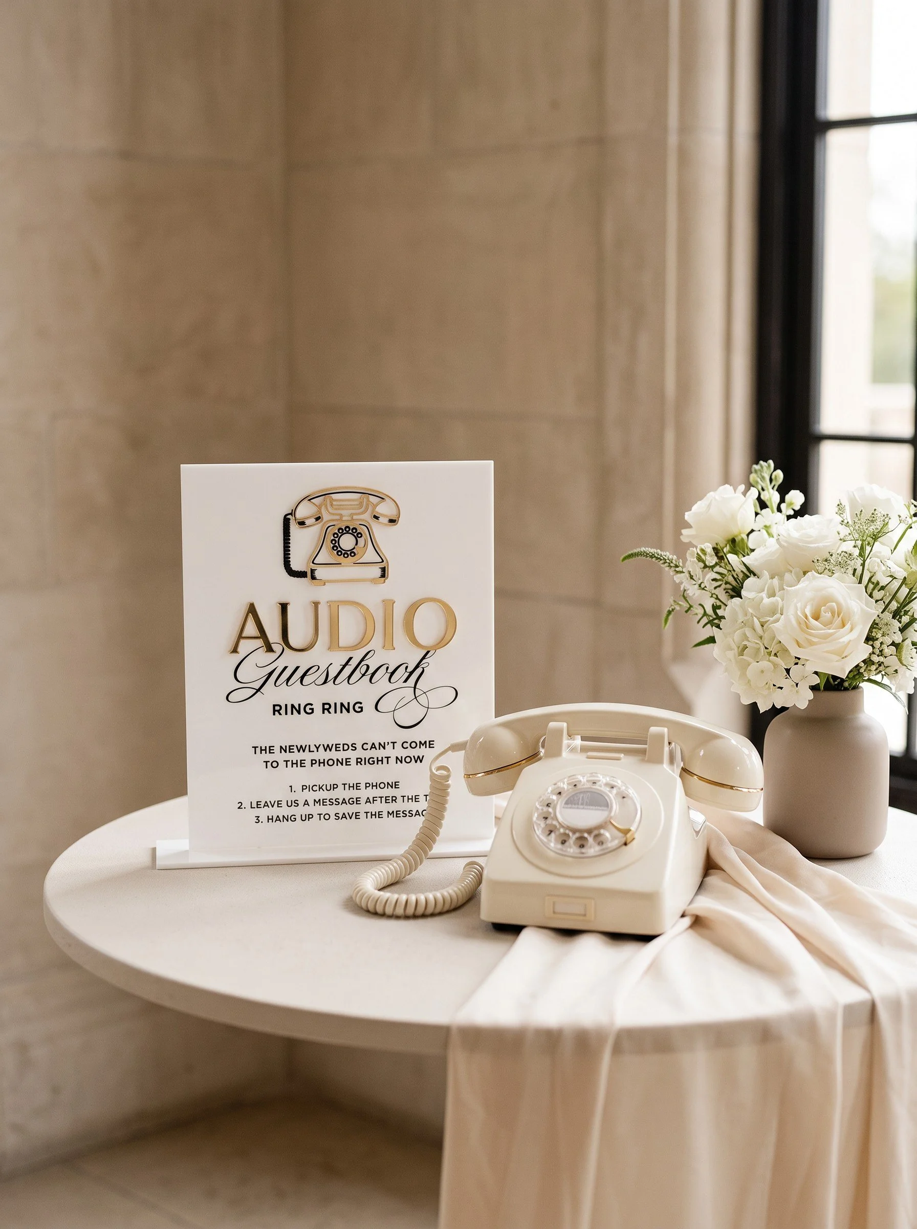 Acrylic Ring Ring audio guestbook sign with raised gold details beside a wedding telephone