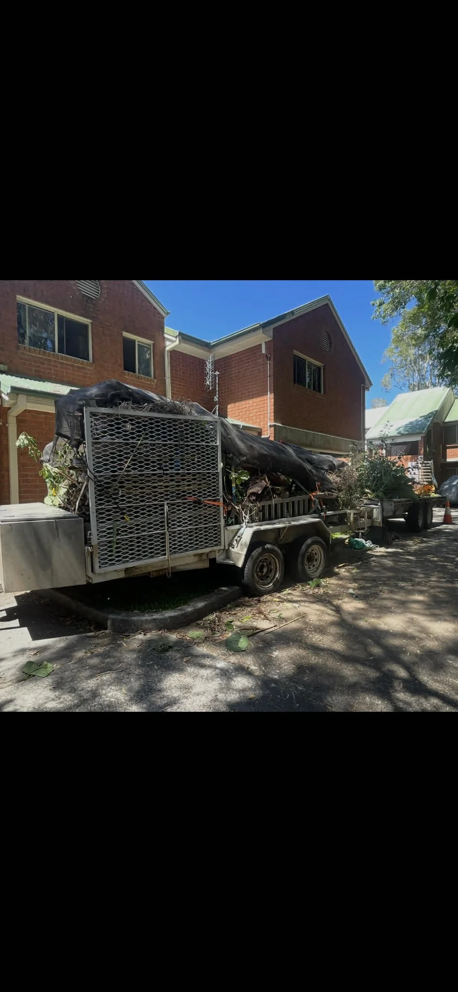 Traffic trailer filled with yard debris parked on a residential street.