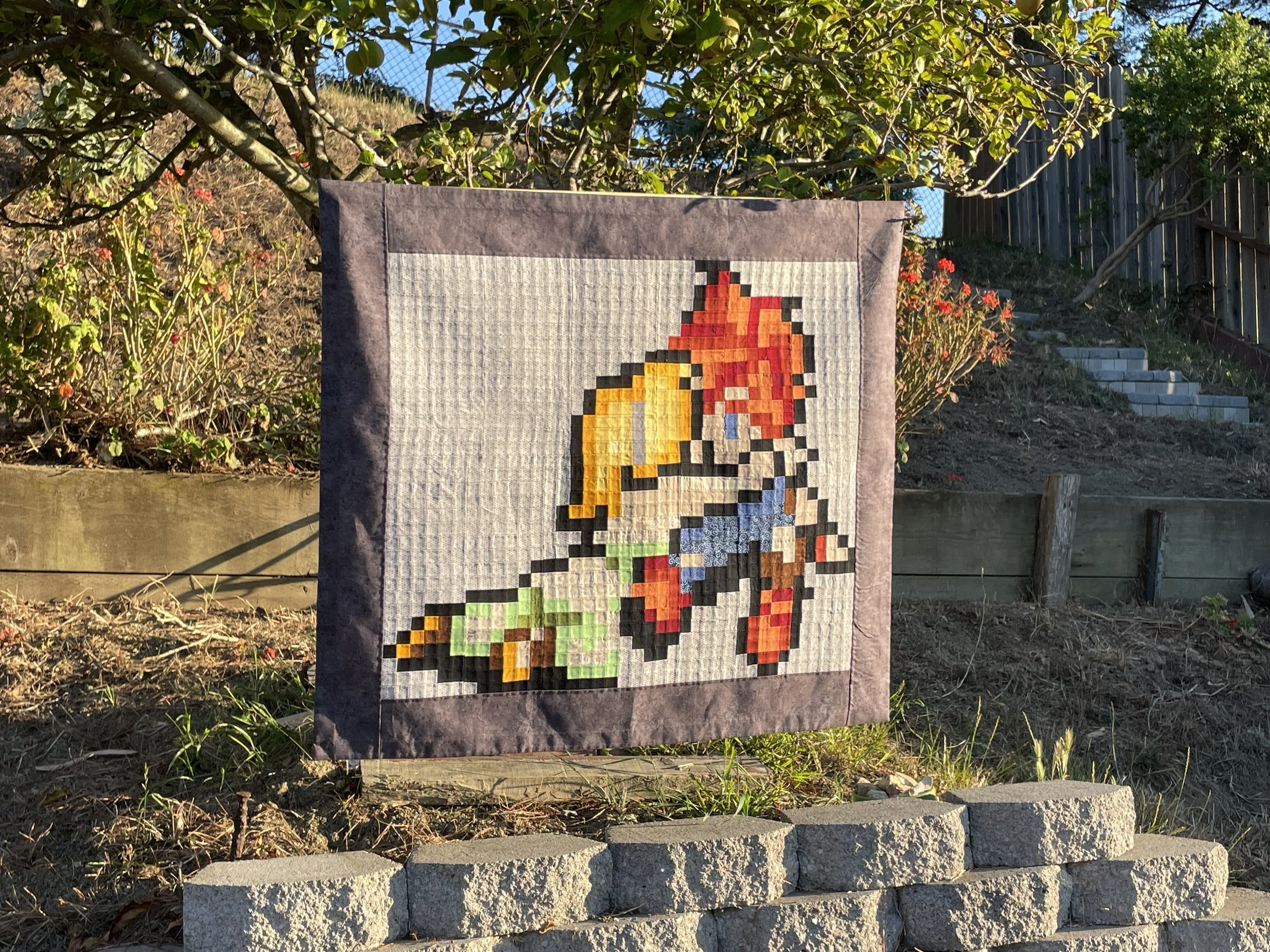 bit art quilt of chrono trigger video game characters displayed in front of an apple tree on a hillside