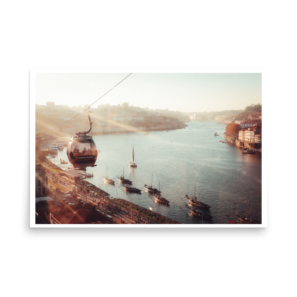 Cable car above the Douro River in Porto at golden hour, with boats on the water below.