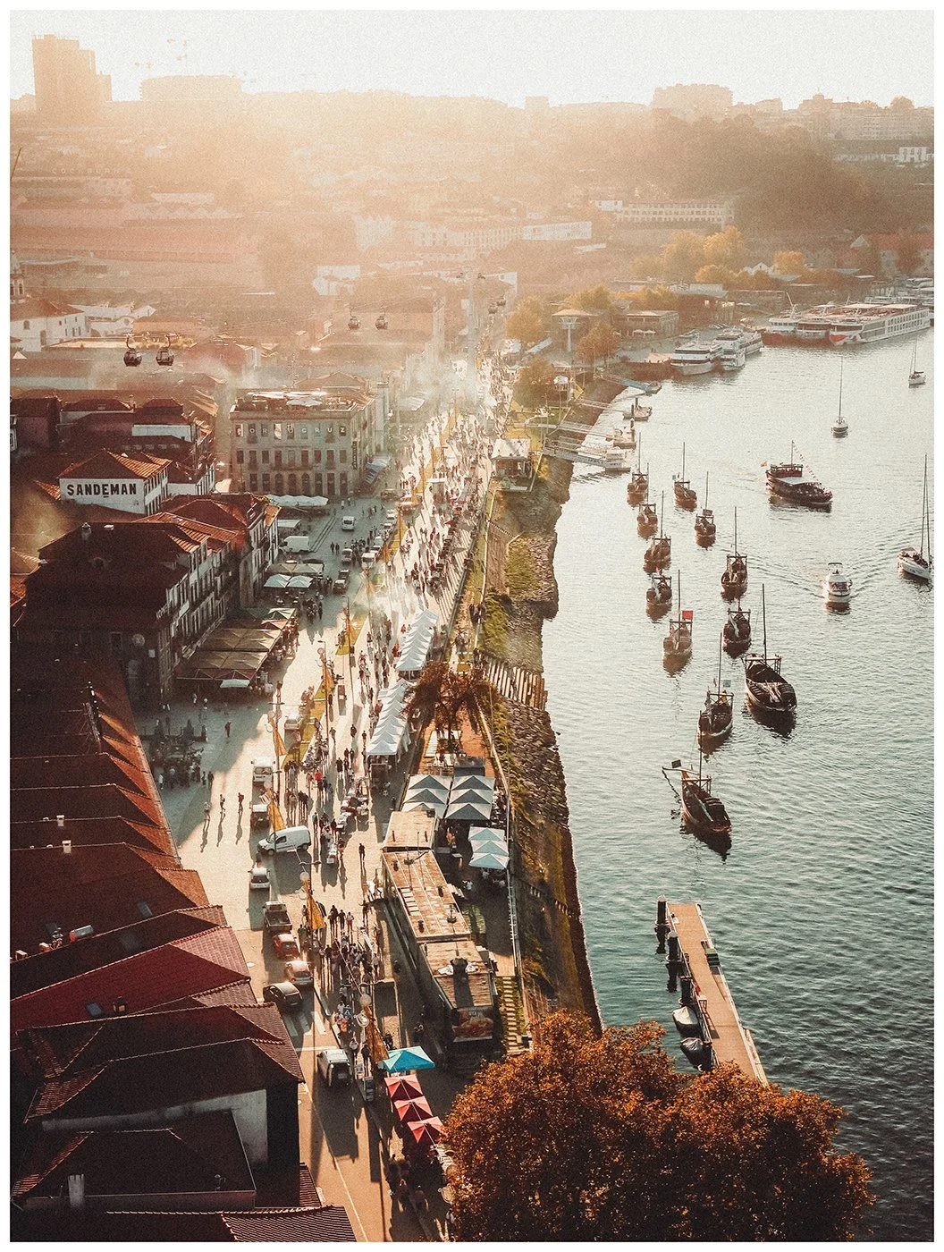 The Douro riverfront stretches into the distance beneath warm evening light, with boats tracing their way through the water below.
