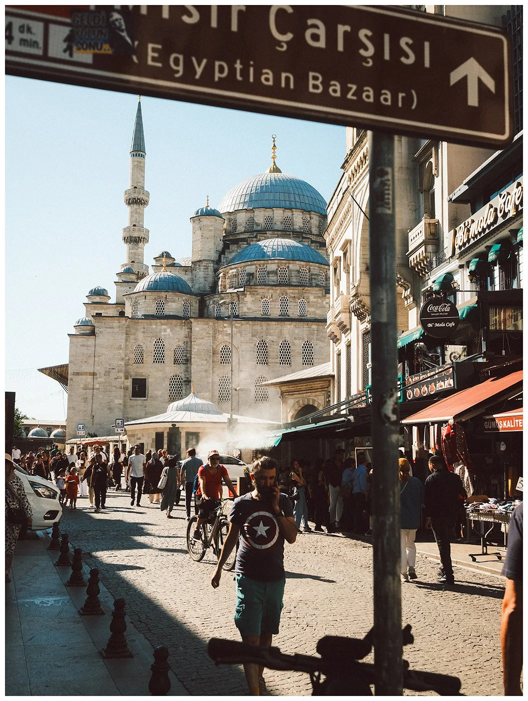 Street life unfolds beneath a sign to the Egyptian Bazaar, with the historic city rising beyond.