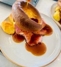 Roast beef with gravy, served with potatoes on a white plate.