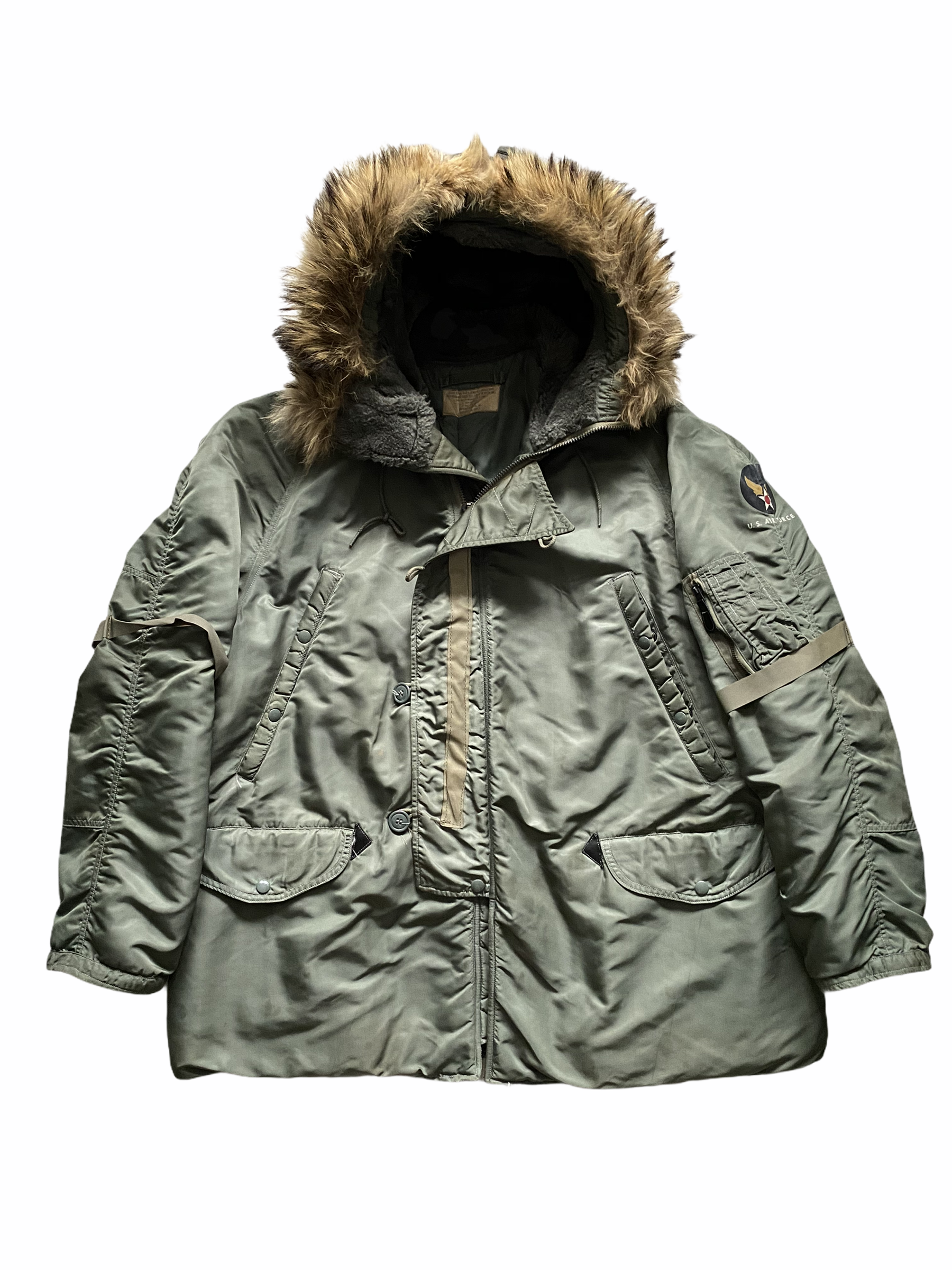 A dark green U.S. Air Force military winter jacket with a fur-lined hood, multiple pockets, and a U.S. Air Force patch on the left sleeve.