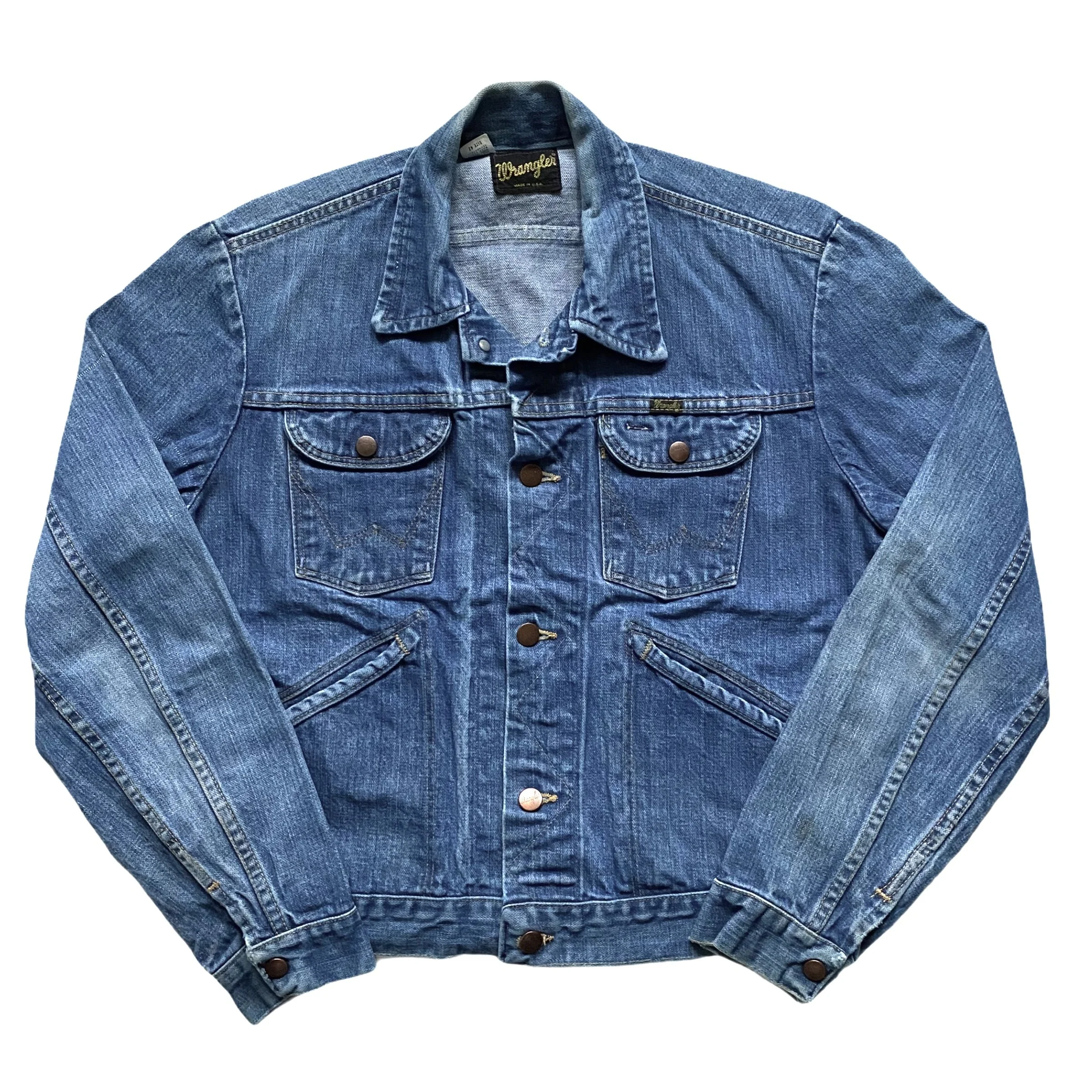 A blue denim Wrangler jacket with metal buttons and front pockets, laid flat with the sleeves crossed.