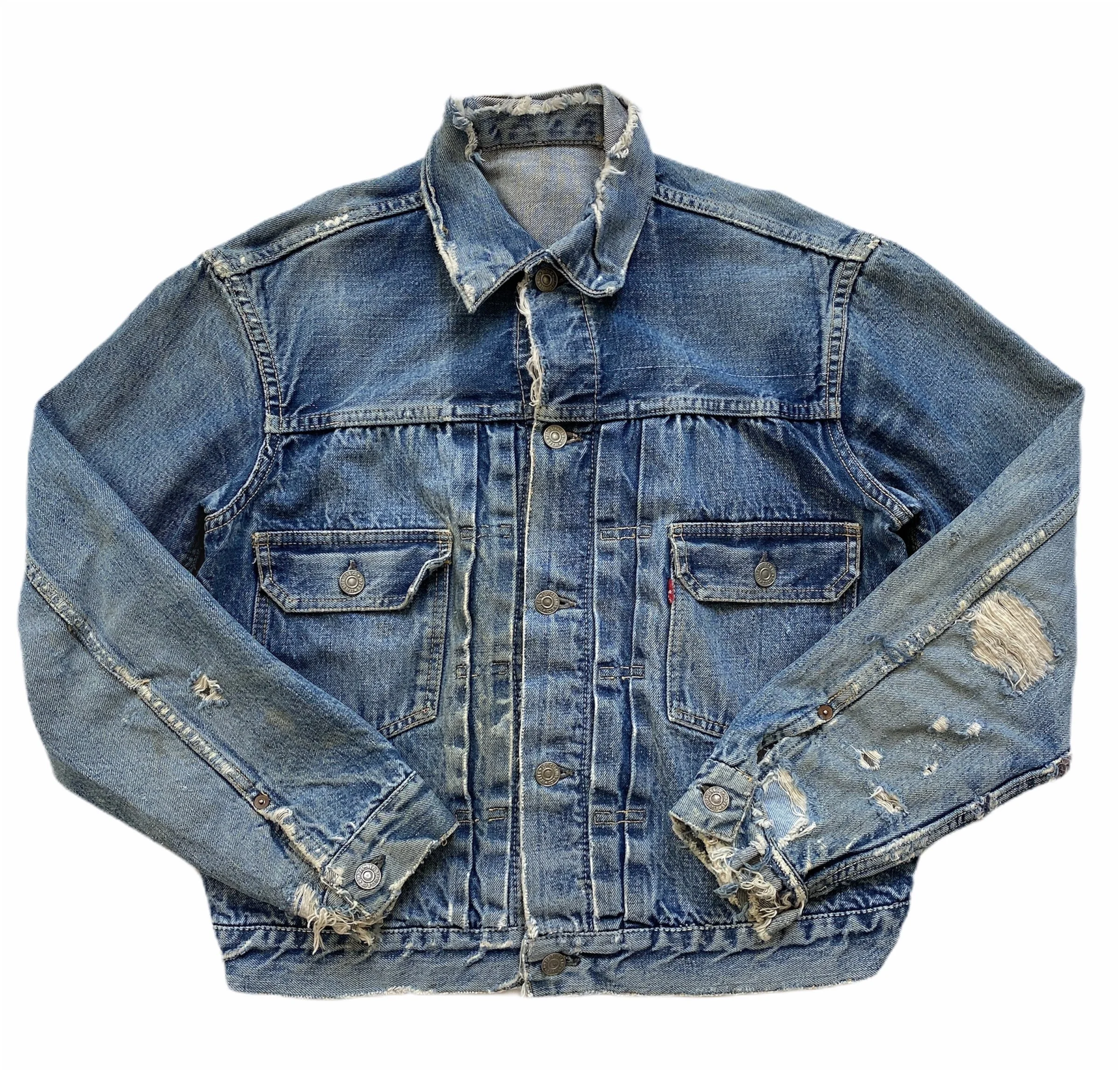 A blue denim jacket with distressed details, metal buttons, and a collar, laid flat against a white background.