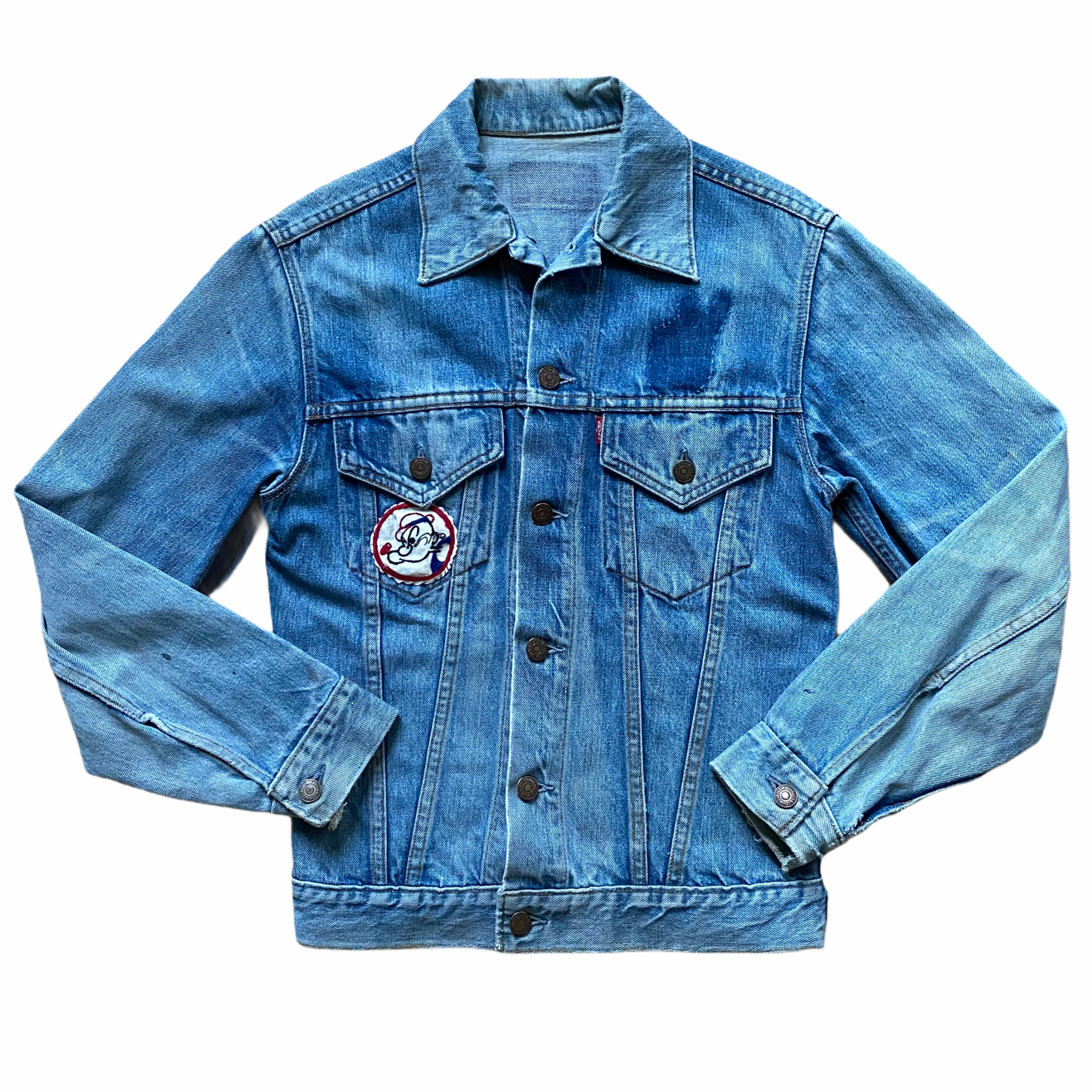 Blue denim jacket with buttons, chest pockets, and a patch of a cartoon character on the lower left side.