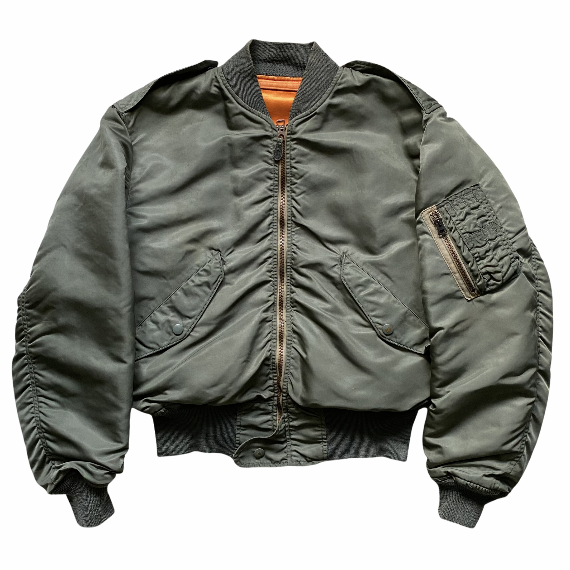 Green military-style bomber jacket with ribbed collar, cuffs, and waistband, featuring a front zipper, shoulder epaulets, and a zippered pocket on the left sleeve.