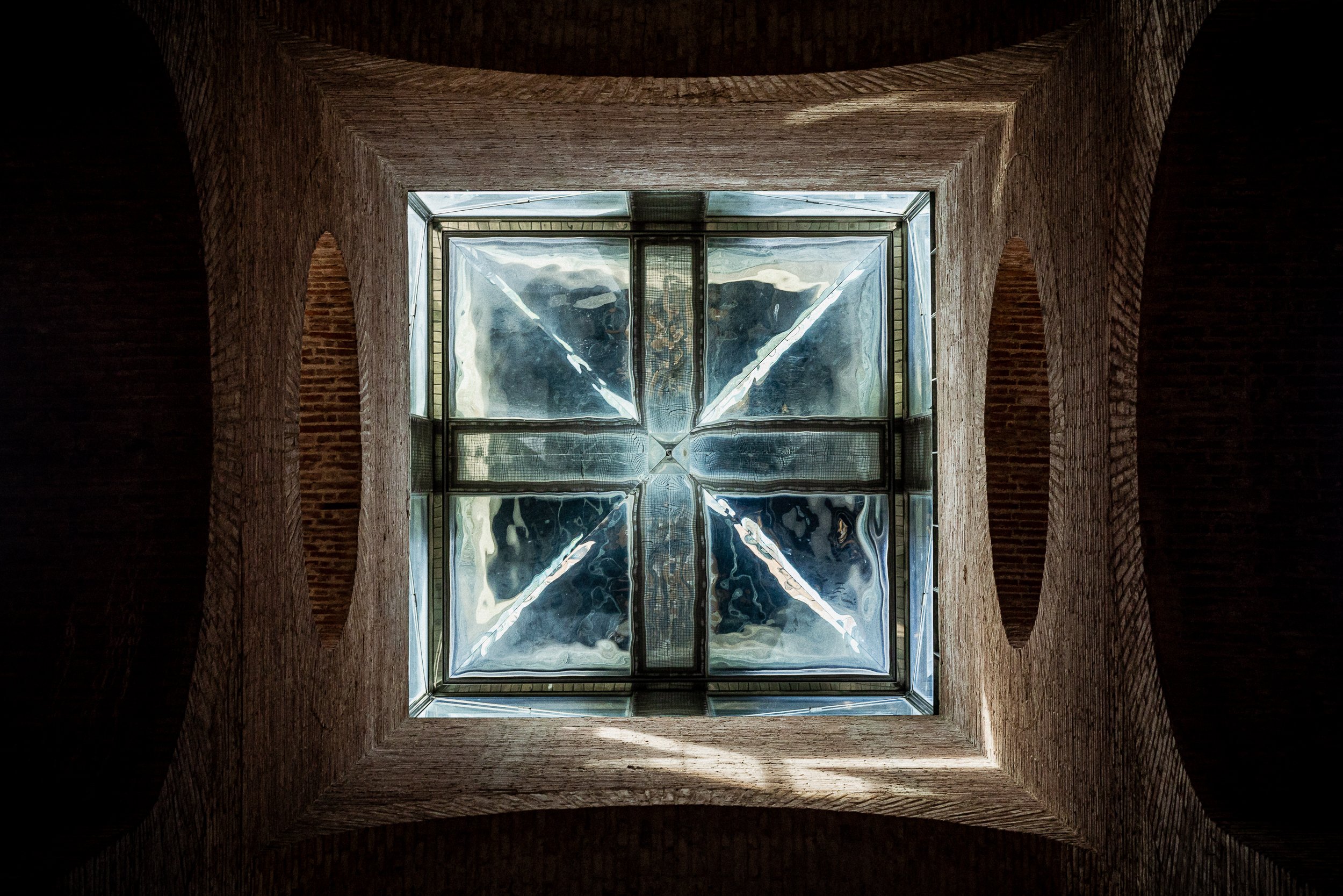 Looking straight up. A square glass skylight set into the brick ceiling.