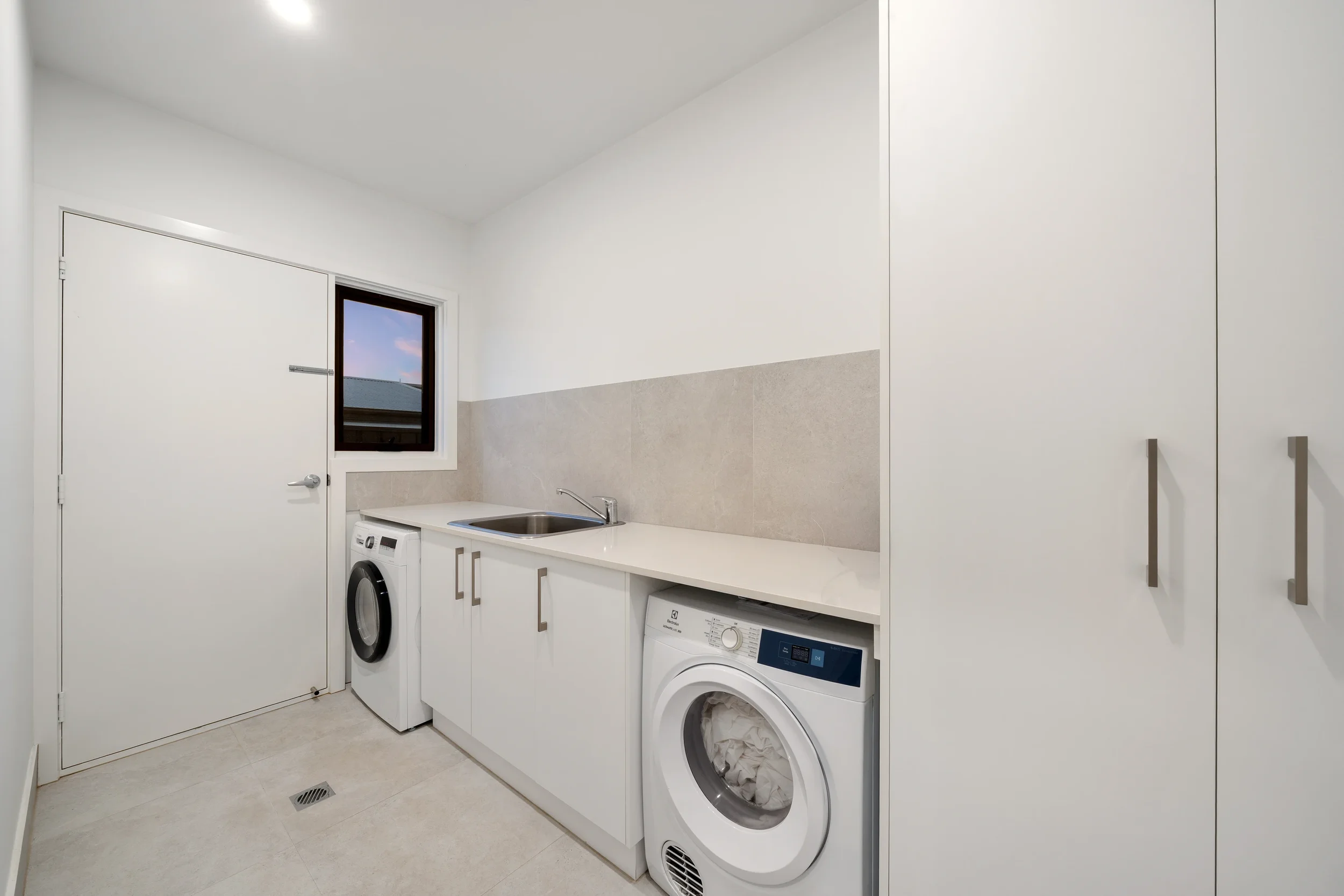 Laundry renovation in Geelong with built-in sink, storage cabinetry and full-size washer and dryer