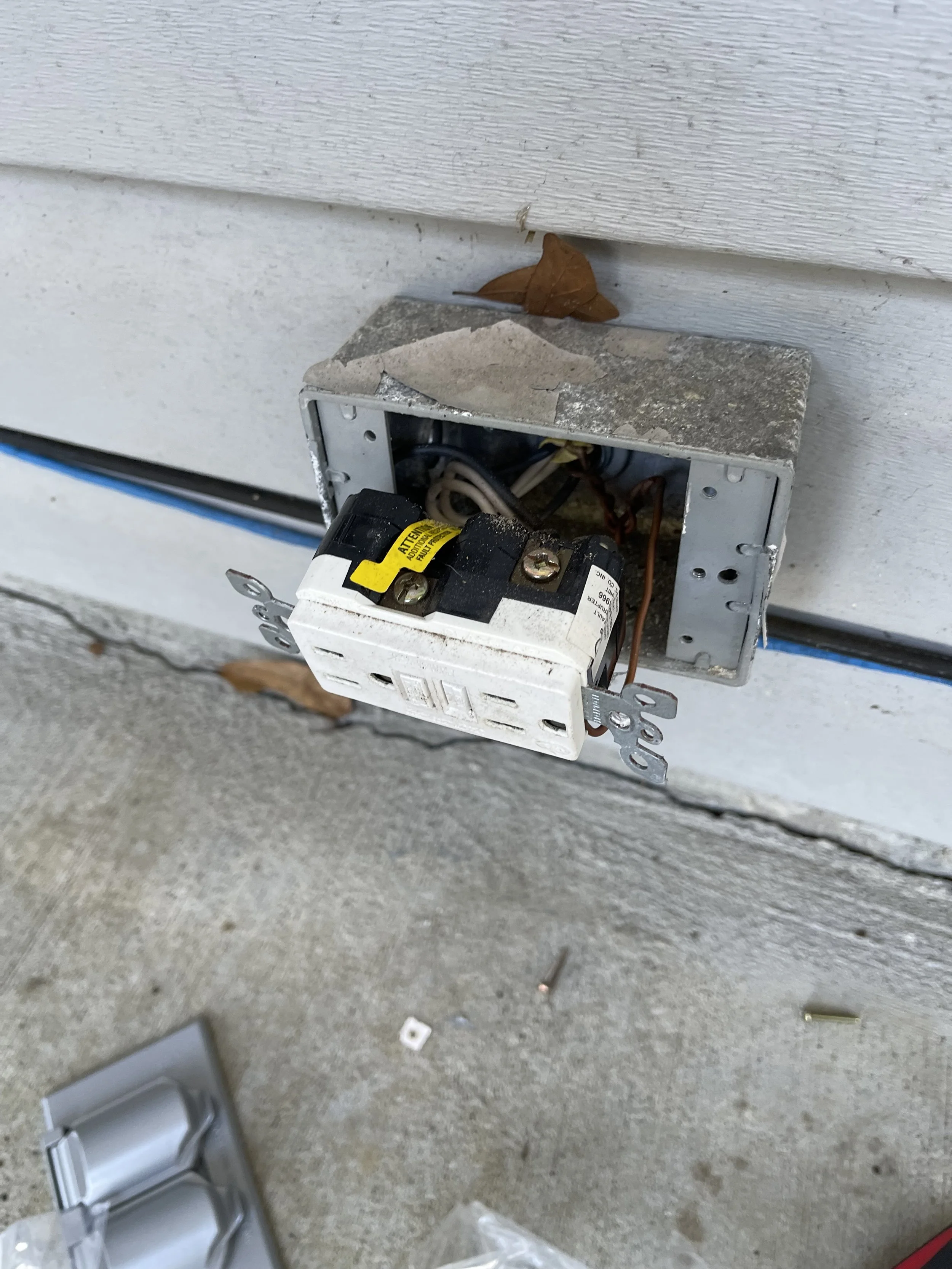 Damaged outdoor electrical receptacle opened for repair.