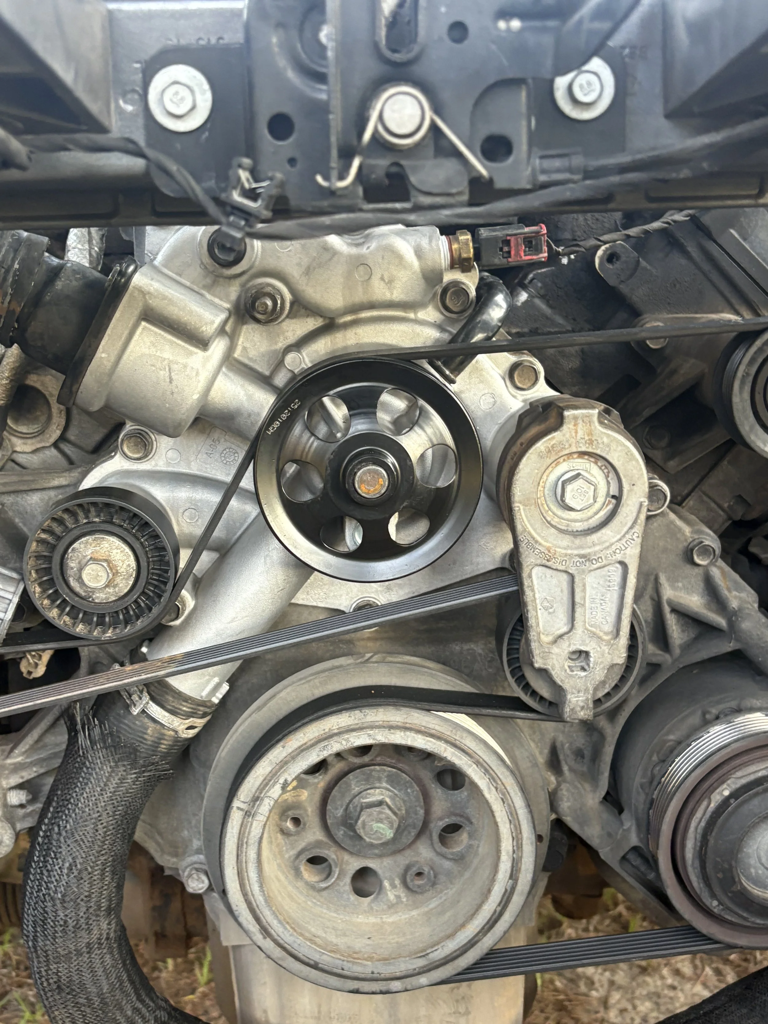 Close-up view of an internal car engine, showing pulleys, belts, and various mechanical components.