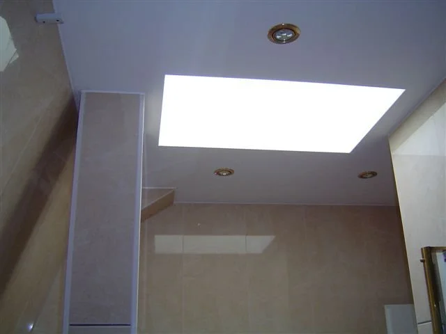 Heller Badezimmerdeckenleuchte mit zwei eingebauten Deckenleuchten und einem Oberlichthimmel.
