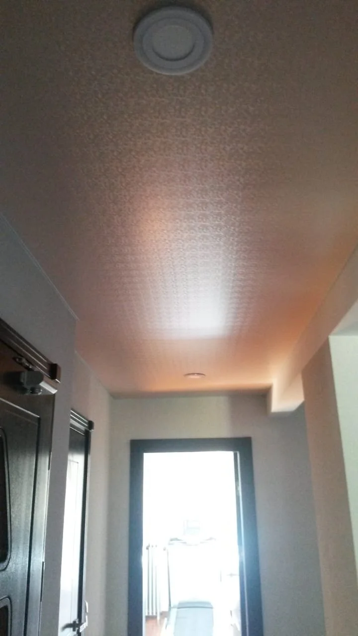 Decke in einem Flur mit einem eingebauten Licht und einem Fenster, das helles Tageslicht hineinscheinen lässt.