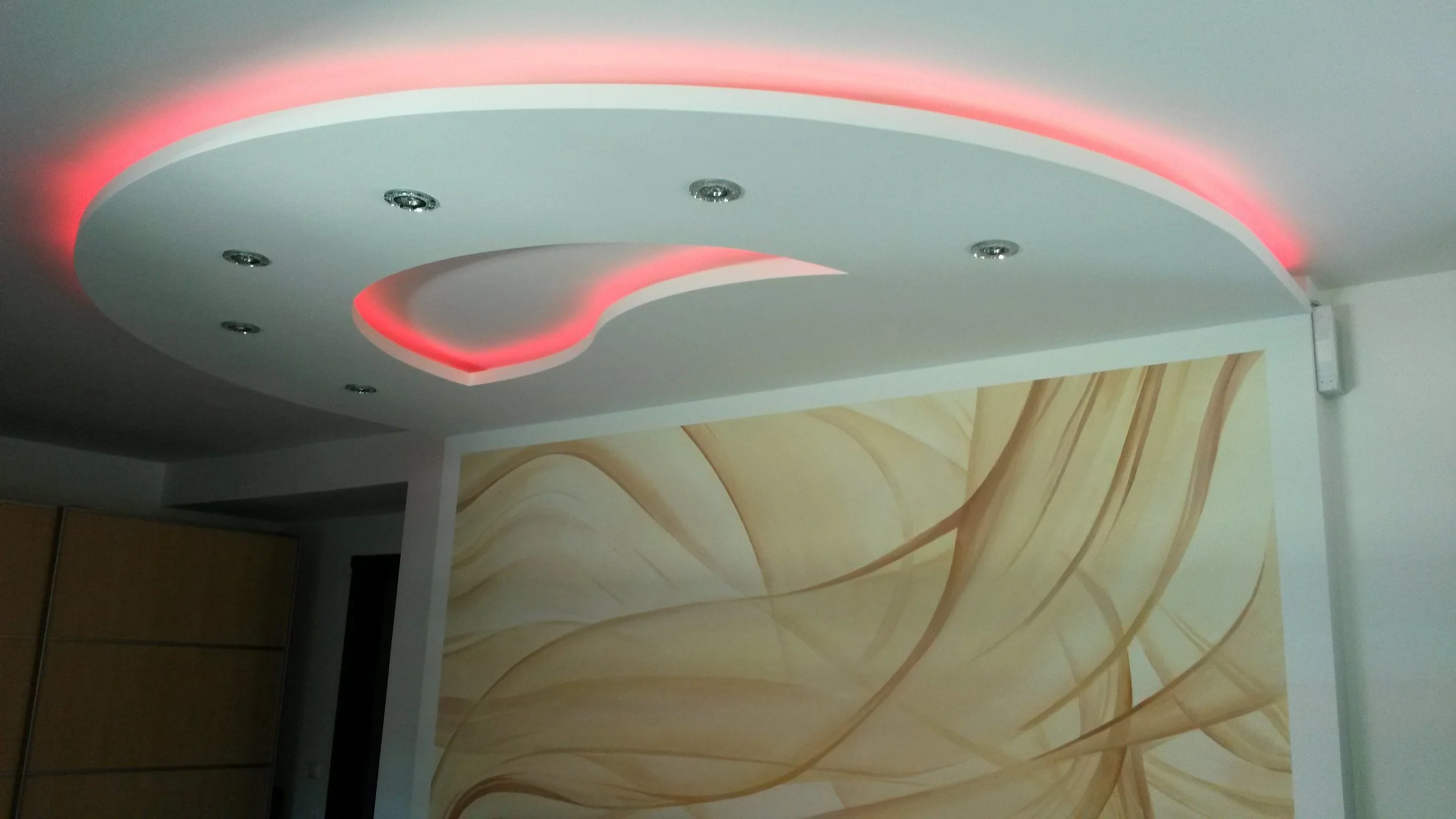 Moderne Raumdecke mit integrierter LED-Beleuchtung in Form eines Herz und mehreren Deckenleuchten.