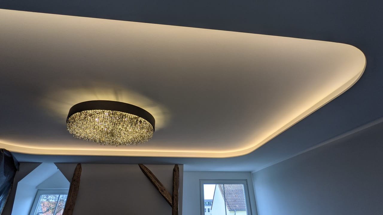 Moderner Raum mit abgehängter Decke und einem dezenten, runden Kronleuchter mit Kristallen.