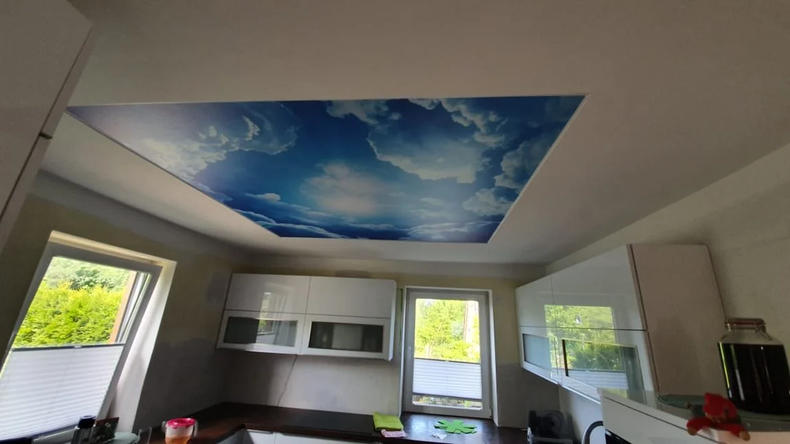 Himmelbild auf Decke in einer modernen Küche mit Fenster und weißen Schränken.