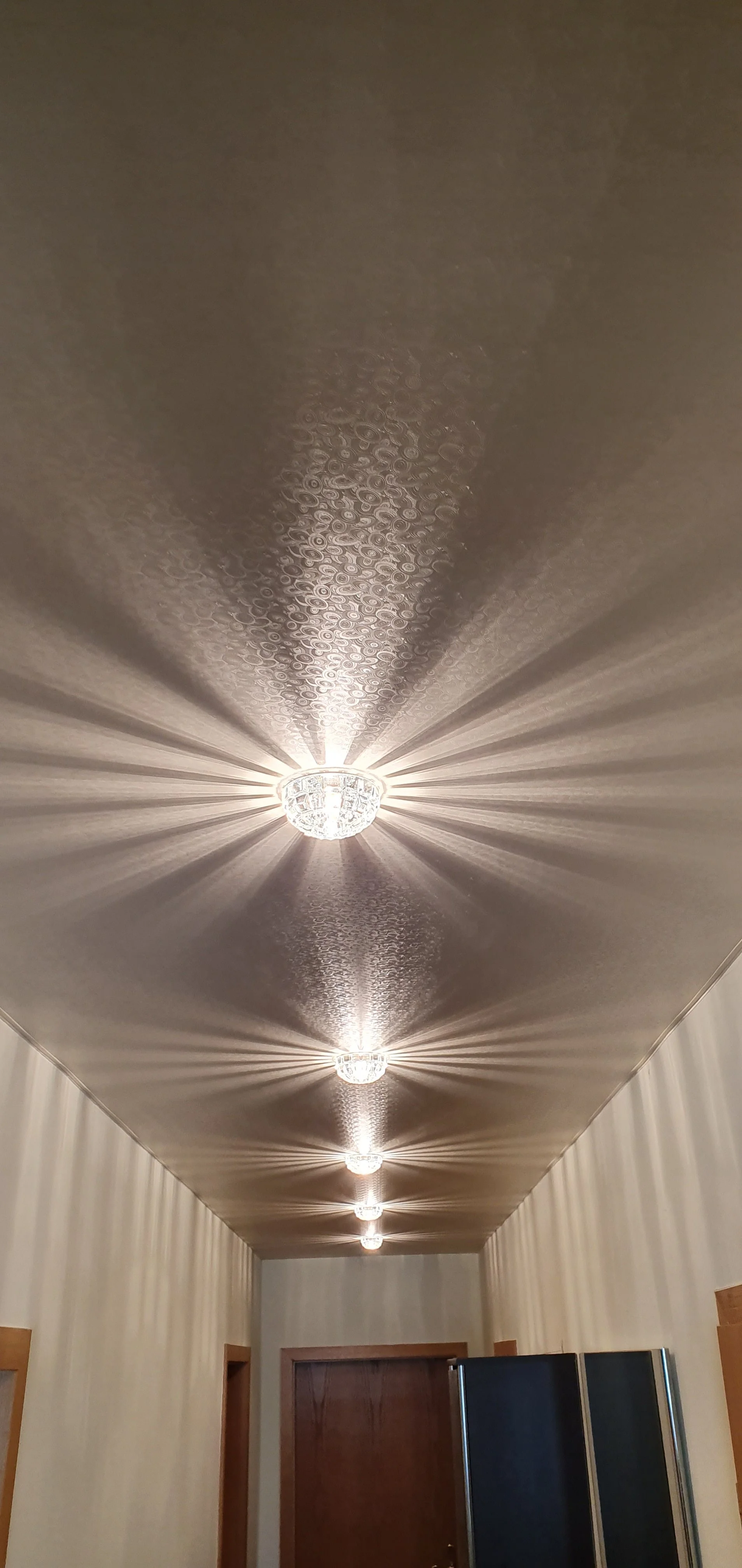 Der Lichtstrahl einer Deckenleuchte an der Decke eines Korridors, der Schattenmuster an der Decke wirft.