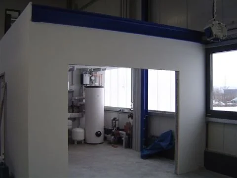 Innenansicht eines Raums mit Wasserboiler, Wasserleitungen und einem Fenster