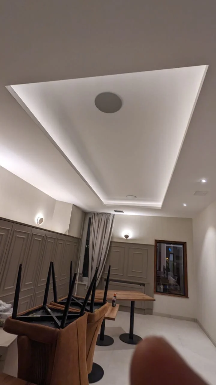 Leeres Esszimmer mit gedecktem Holztisch, Stühlen auf dem Kopf liegend, an der Wand ein Fenster, an der Decke eine Deckenleuchte und versteckte Beleuchtung, unordentliches Zimmer.