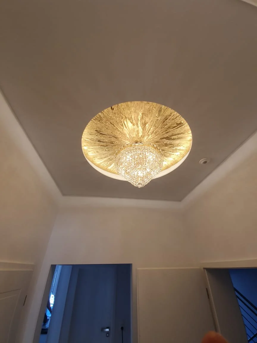 Deckenleuchte mit Kristallkugel in einem modernen Raum, beleuchtet die Decke mit warmem Licht.